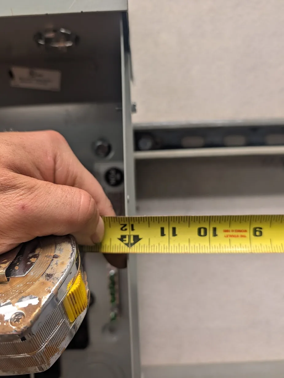Tape measure between the main panel and subpanel showing exactly 12\" of spacing
