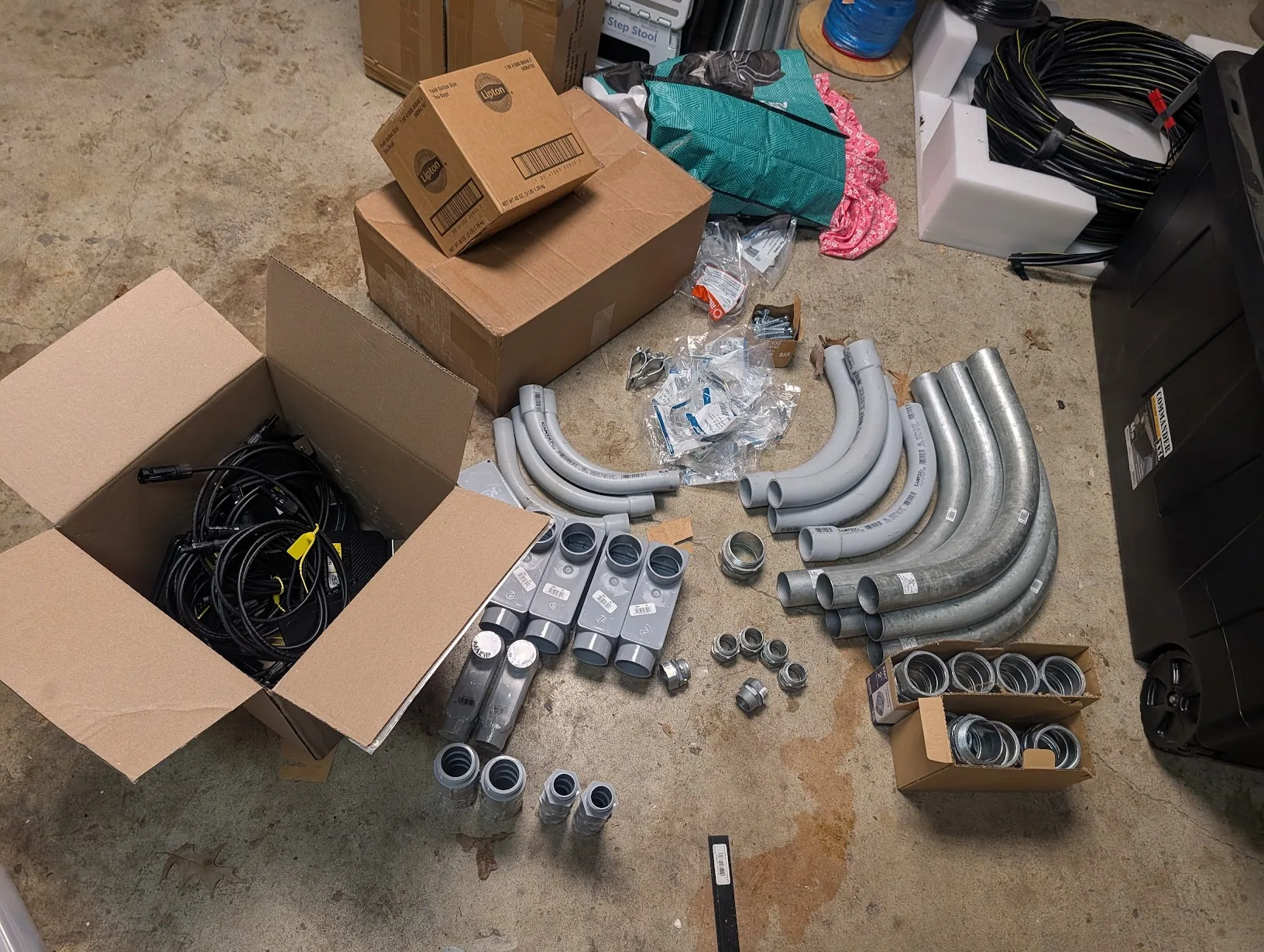 Pile of EMT fittings — 45s, 90s, couplers, connectors — staged for the install