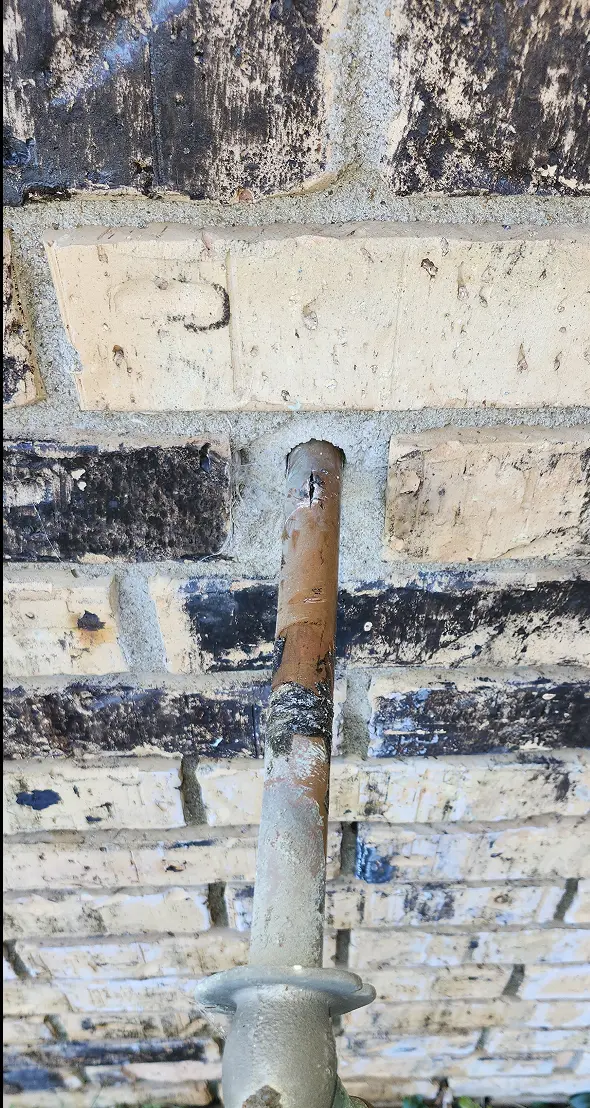 Picture showing old spigot being removed from house, with burst pipe