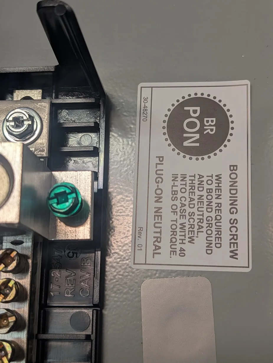 Close-up of the green bonding screw and the BR-style “bonding screw - when required” warning label