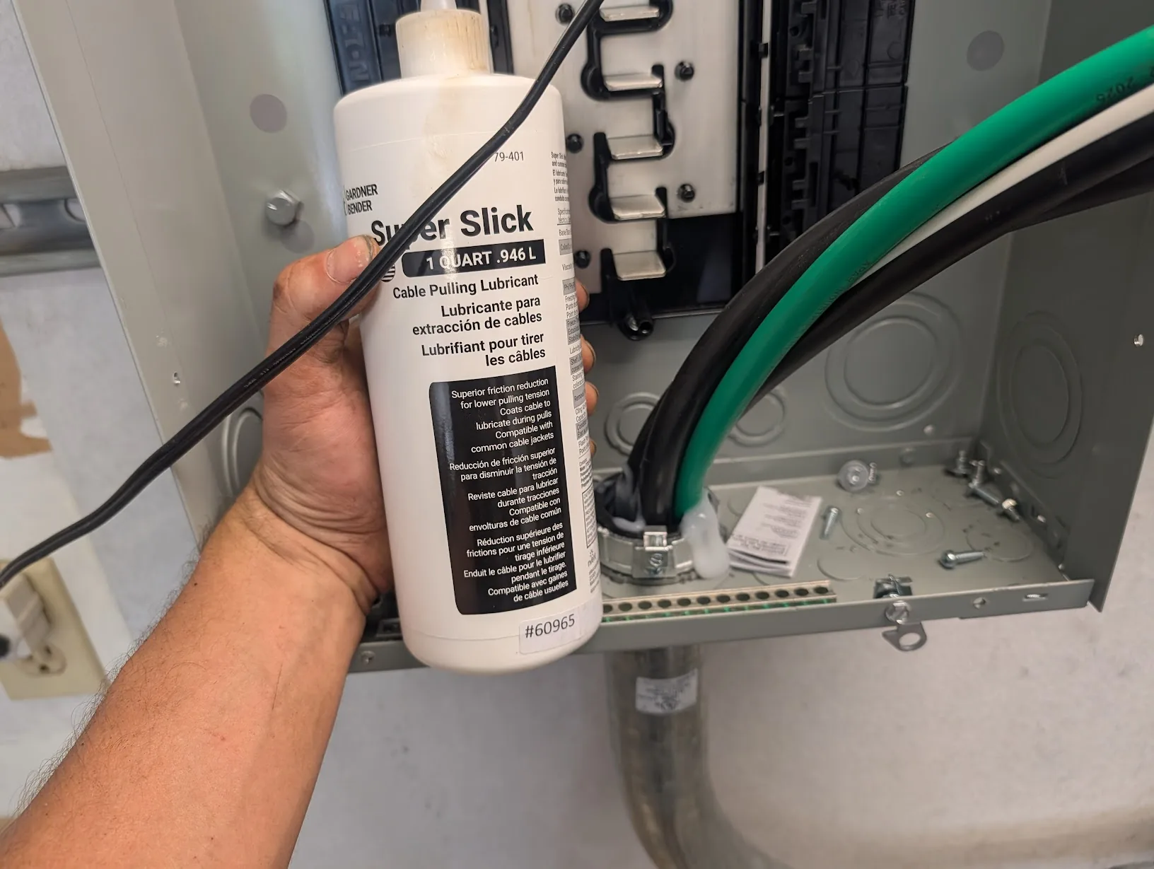 Quart bottle of Gardner Super Slick cable pulling lubricant held in front of the open main panel