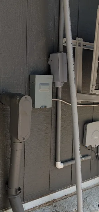 Exterior wall with the FS-style box mounted and conduit roughed in alongside the mini-split disconnect