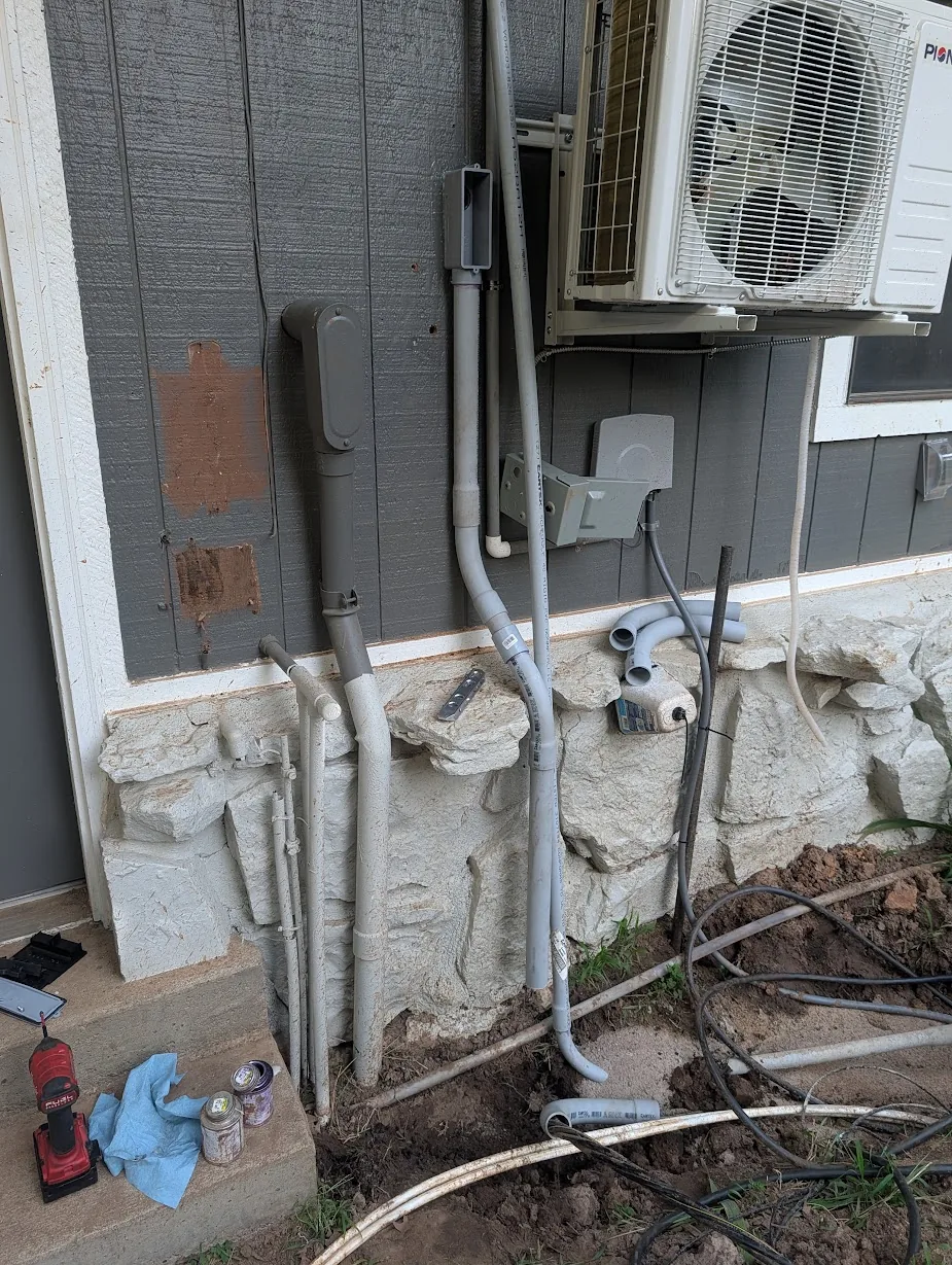 Exterior conduit roughed in along the stone wall near the mini-split