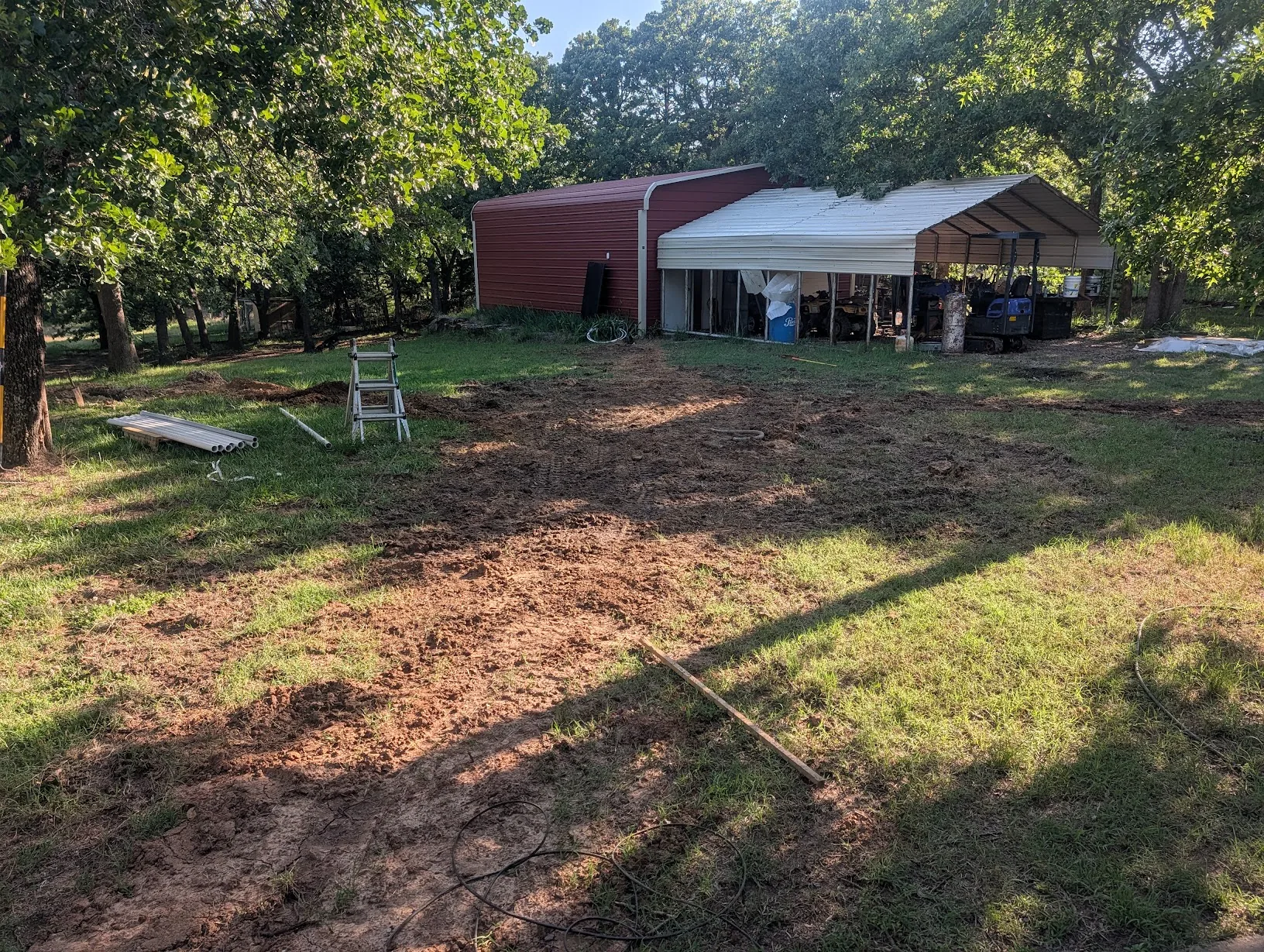 Trenches backfilled across the yard with the shop in the background